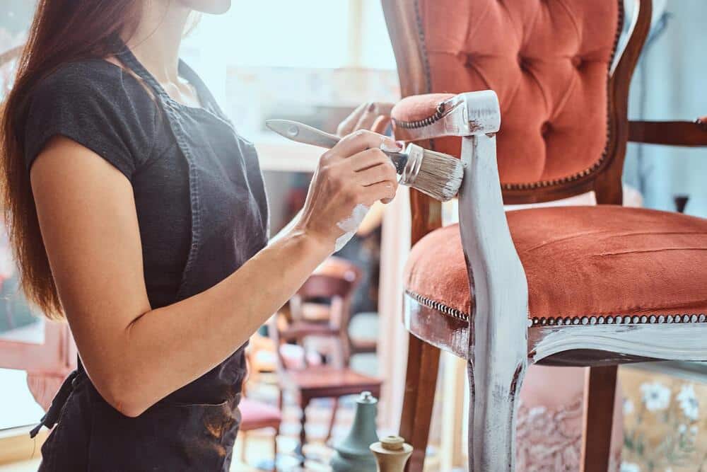 artista femenina pintando silla vintage color blanco